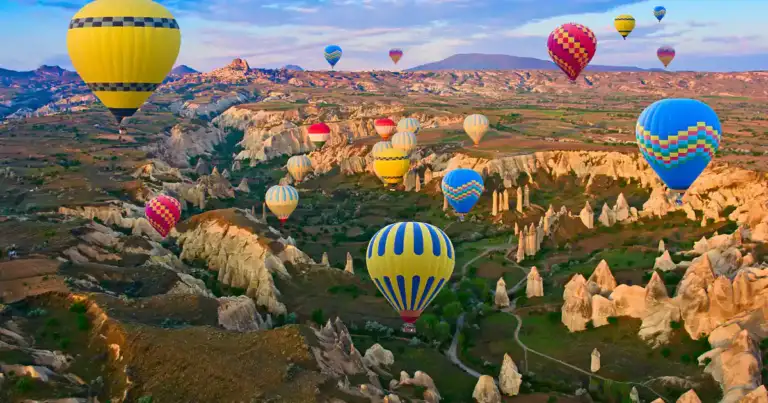 Globos aerostáticos multicolores sobre los valles y formaciones rocosas de Capadocia al amanecer.