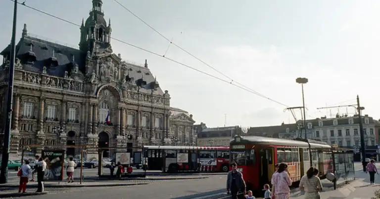 Edificio histórico en plaza francesa con tranvía rojo y personas