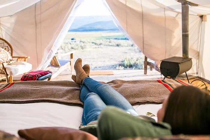 Interior de tienda glamping con cama y vista al lago