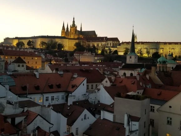 Paisaje urbano medieval con castillo coronando la ciudad y torres al atardecer