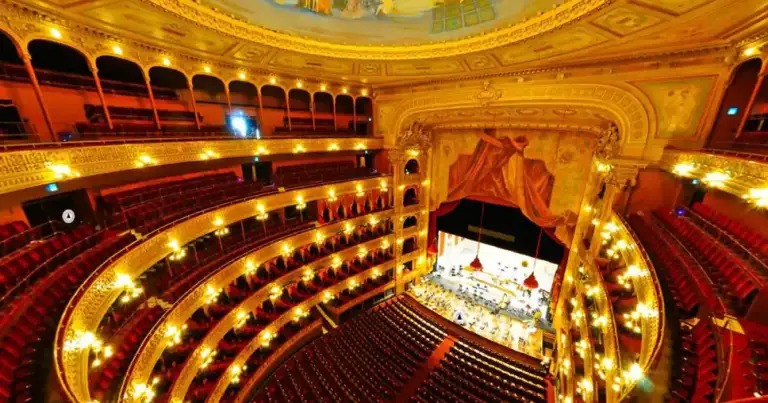 Interior de teatro con múltiples balcones rojos y dorados iluminados