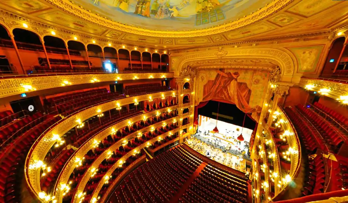 Interior de teatro con múltiples balcones rojos y dorados iluminados