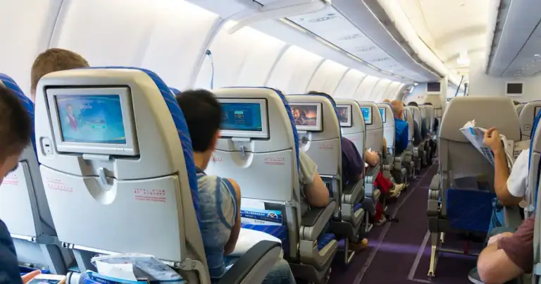 cabina de un avion, se ven pasajeros sentados