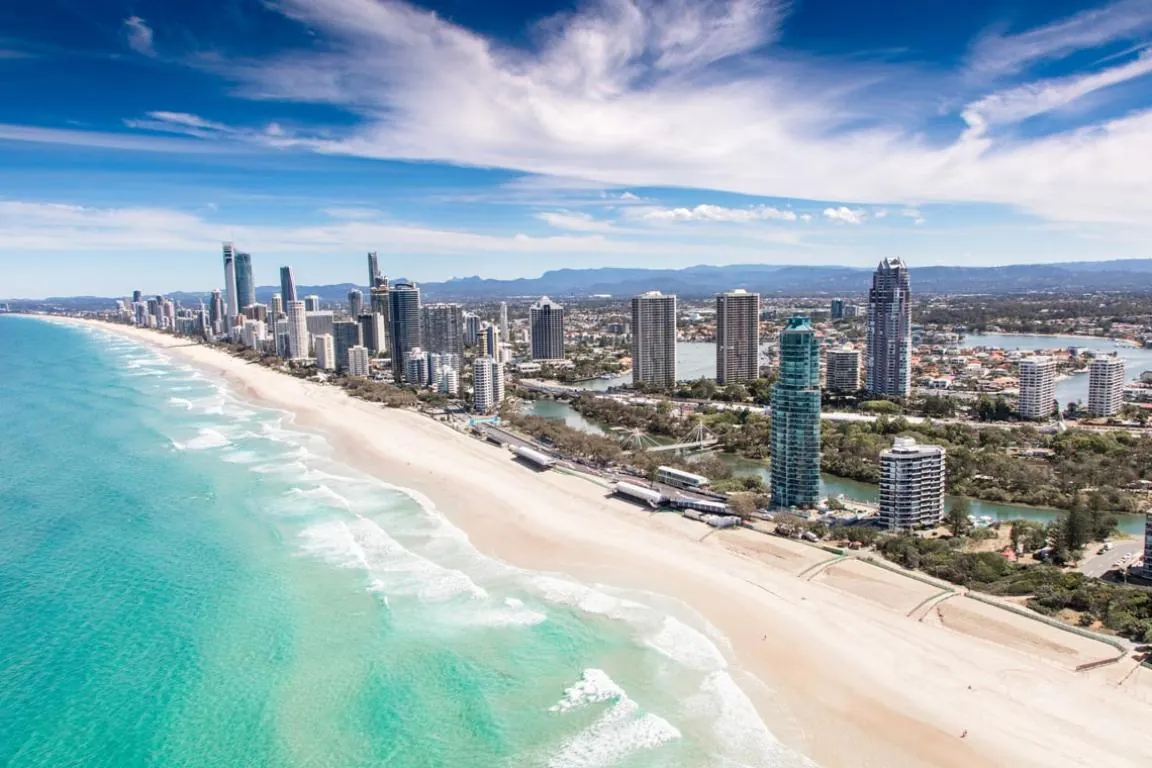 Playa con aguas turquesas, arena blanca y rascacielos