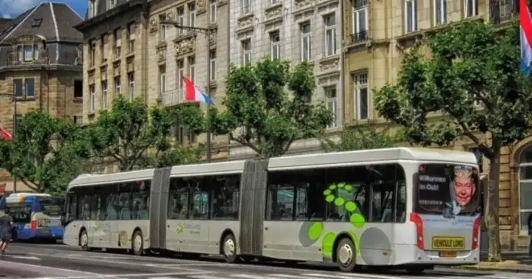 Autobús moderno blanco en calle de Luxemburgo frente a edificios históricos