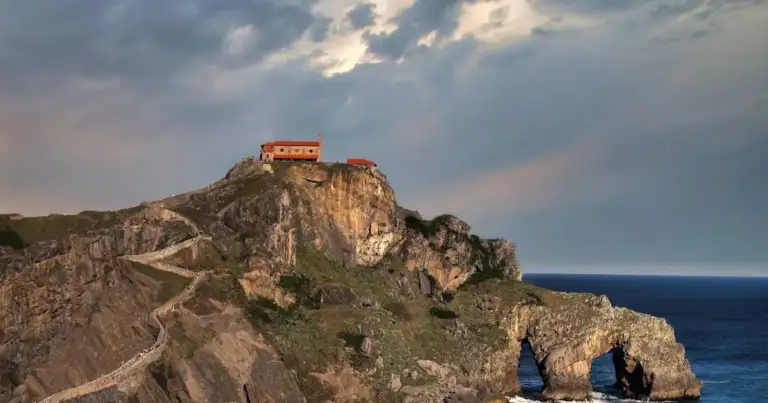 Ermita de San Juan de Gaztelugatxe sobre el acantilado frente al mar Cantábrico, al atardecer.