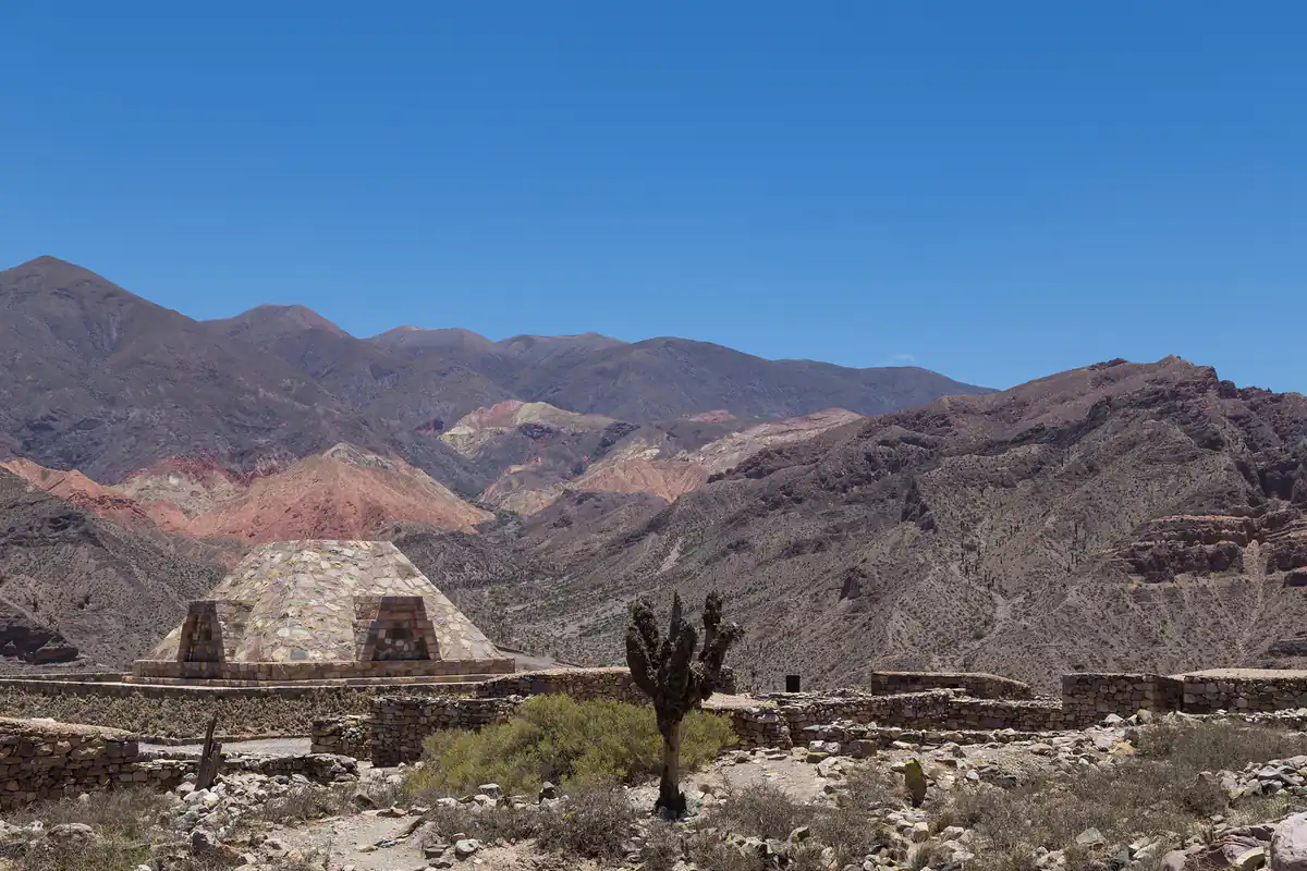 Ruinas de construcción histórica con montañas multicolores bajo cielo azul