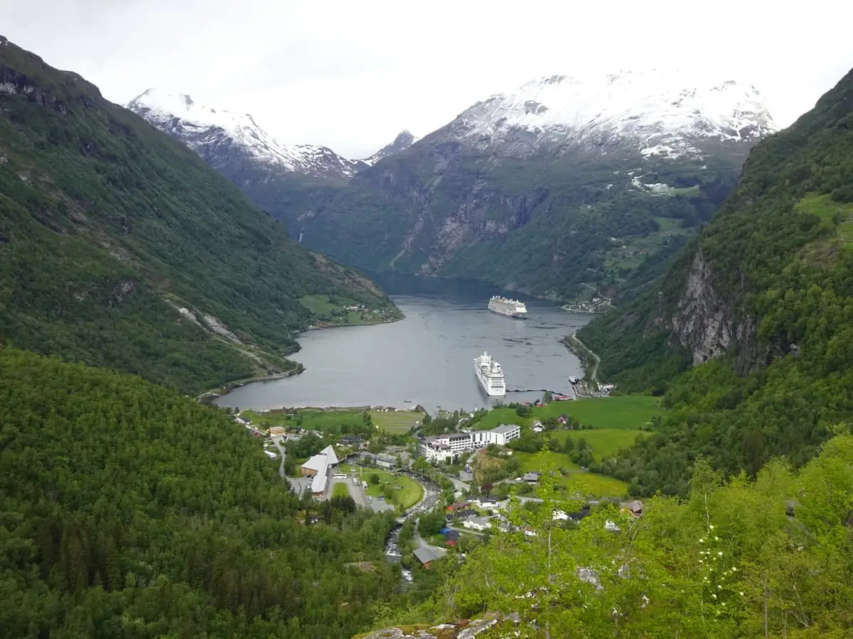 Vista del pueblo de Geiranger y del fiordo desde lo alto, con cruceros anclados entre montañas nevadas