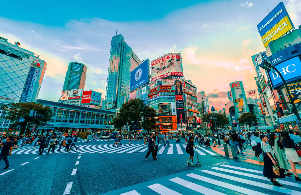 Cruce de Shibuya con multitud de peatones entre rascacielos y señalética neon