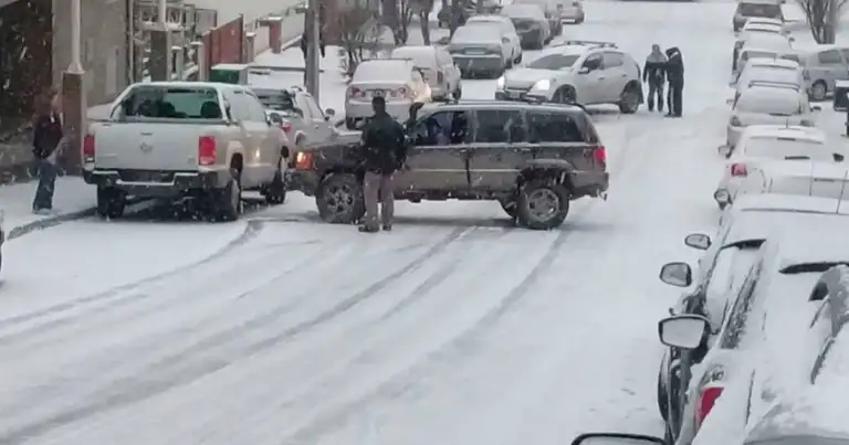 Calle de montaña completamente cubierta de nieve con autos