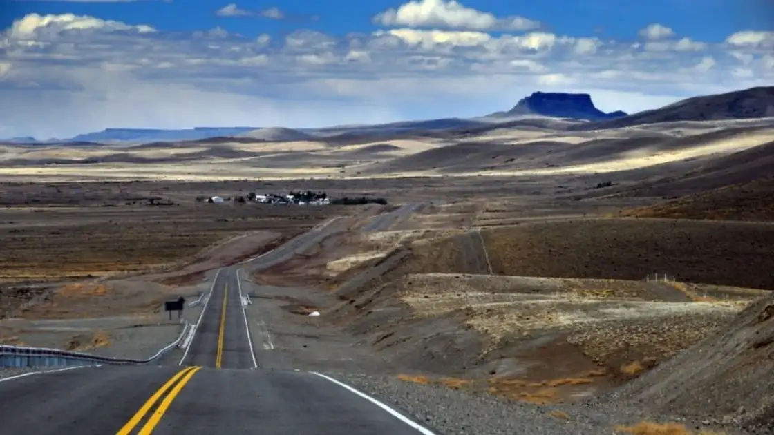 Carretera recta atravesando paisaje árido con montaña de fondo