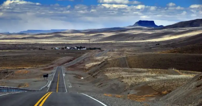 Carretera recta atravesando paisaje árido con montaña de fondo