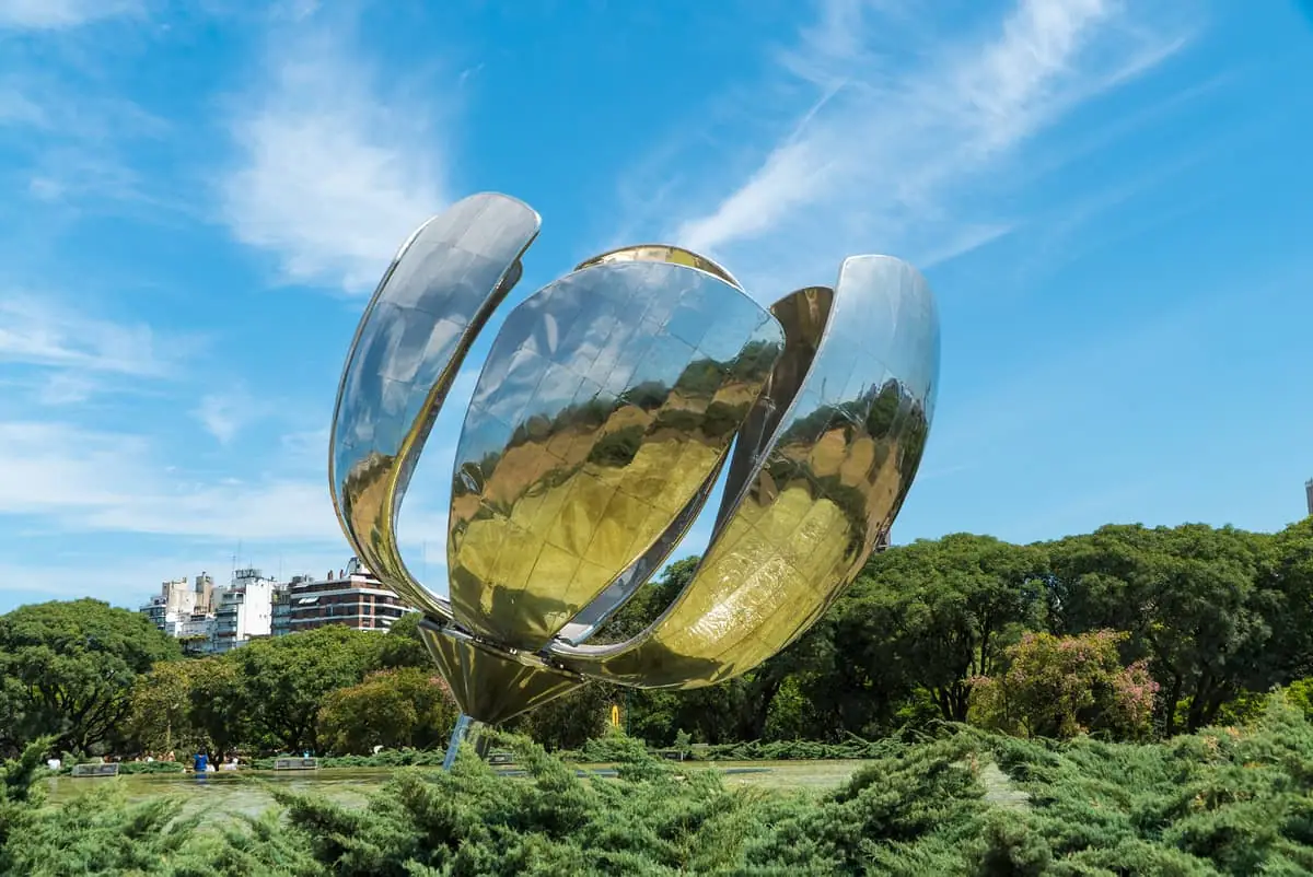 Escultura moderna de flor plateada reflectante con cielo azul