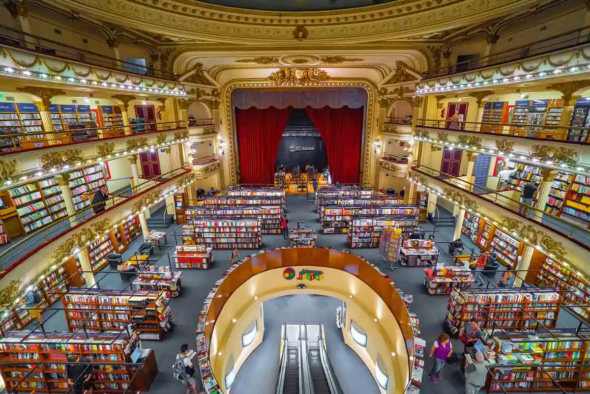 Interior teatral de librería con múltiples pisos y escalera central