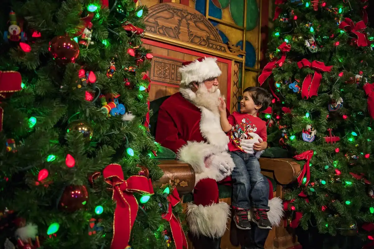 Papá Noel posando con niña pequeña bajo decoraciones navideñas