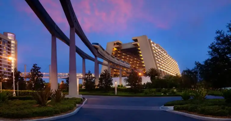 Hotel moderno iluminado al atardecer con viaducto sobre él