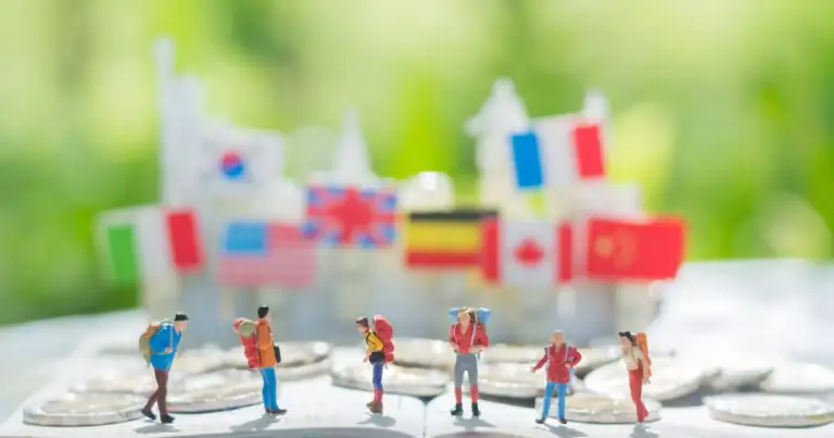 Figuras de turistas en miniatura sobre mapa con banderas