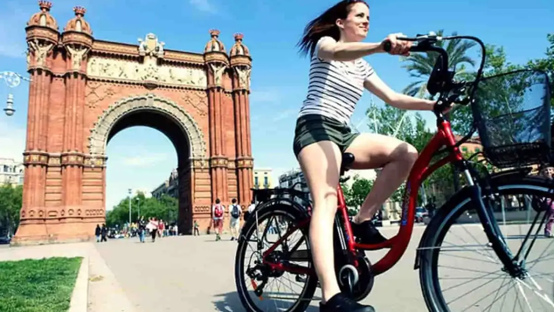 En Barcelona una mujer en Bicicleta pasea frente a un arco