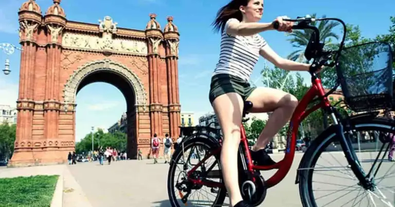 En Barcelona una mujer en Bicicleta pasea frente a un arco