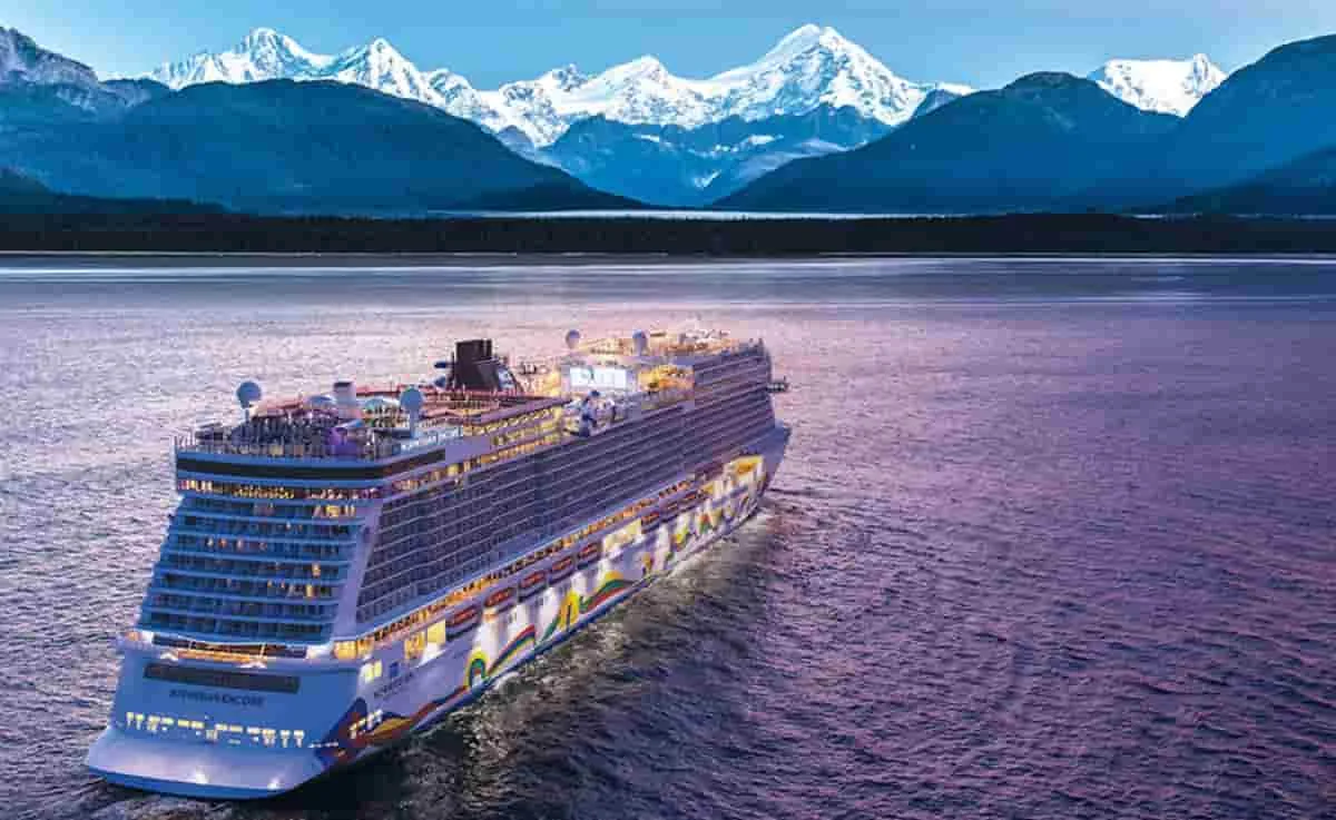 Crucero blanco navegando en agua azul con montañas nevadas al fondo