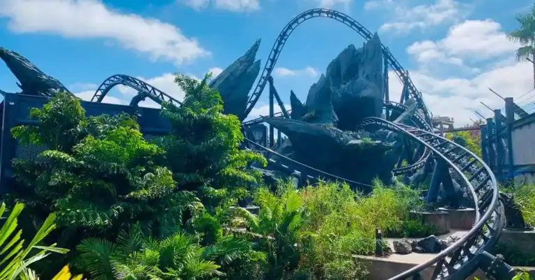 Montaña rusa con vías azul y negra entre vegetación tropical, trazando curvas acrobáticas