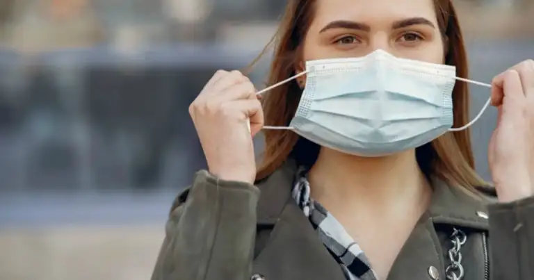 Persona quitándose mascara quirúrgica de color blanco con las manos