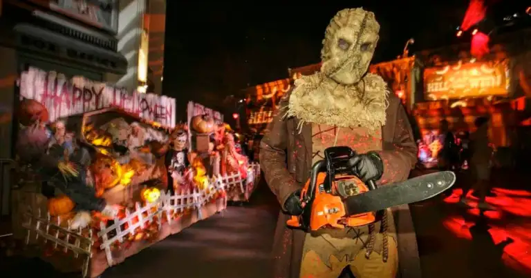 Personaje de película de horror con máscara blanca sosteniendo sierra, en evento nocturno