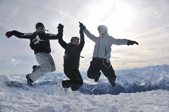 Tres personas saltando de alegría en nieve con montaña