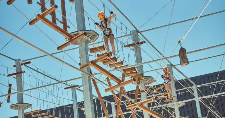 Personas navegando circuito de obstáculos aéreos en estructura de cables y vigas de madera