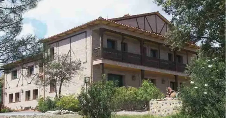 Casa rural mediterránea de dos pisos con terraza y patio jardín rodeado de árboles