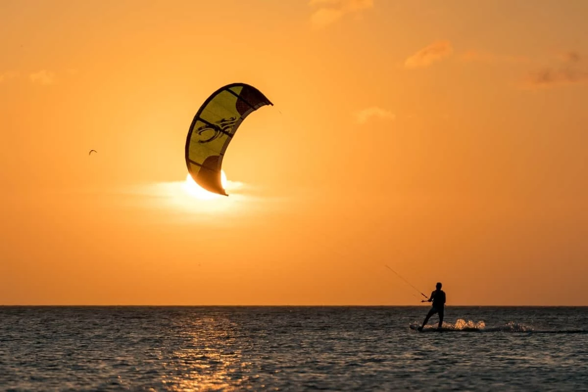 Practicante de kitesurf deslizándose sobre las olas con cometa de colores
