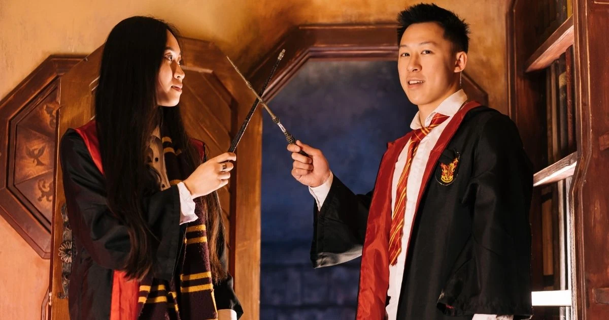 Dos personas vestidas como magos sosteniendo varitas mágicas dentro de decorado fantástico