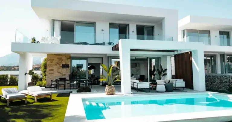 Mansión moderna blanca de dos pisos con piscina azul turquesa y amplias terrazas