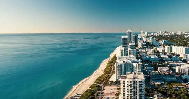 Playa de arena blanca con línea de rascacielos modernos en horizonte urbano costero