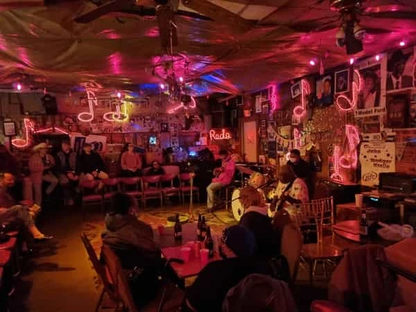 Interior de club de blues en Clarksdale con luces de neón rojo y personas disfrutando