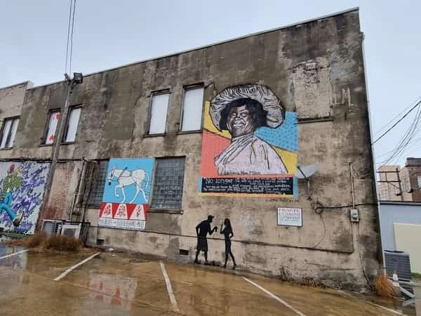 Mural de arte callejero en edificio de ladrillo con retrato de persona