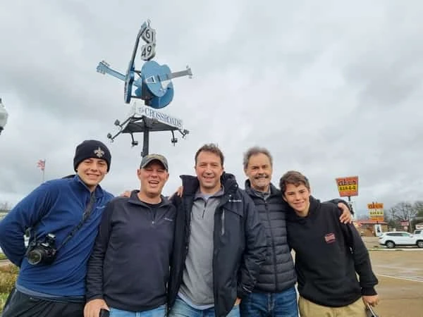 Cinco personas paradas bajo escultura metálica de veleta
