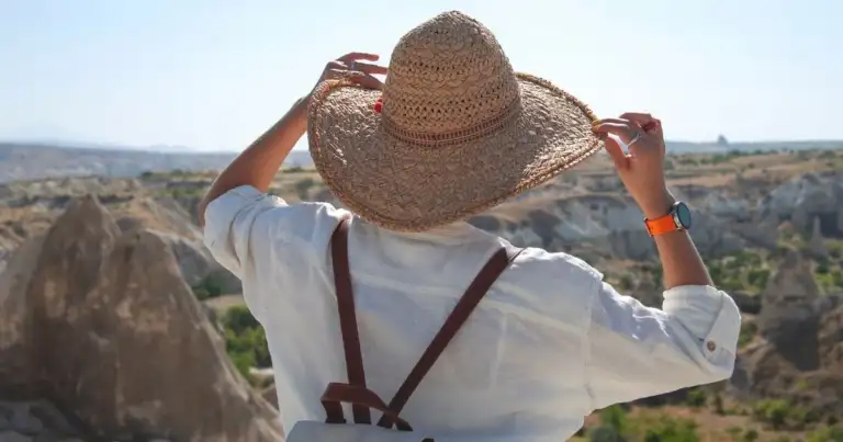 Persona con sombrero de paja observando paisaje desértico con formaciones rocosas erosionadas
