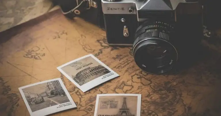 Cámara fotográfica vintage negra con fotografías polaroid sobre mapa mundial antiguo