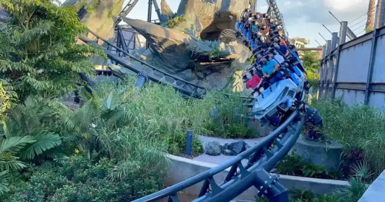 Montaña rusa de rieles azul intenso en parque temático con decorados fantásticos alrededor