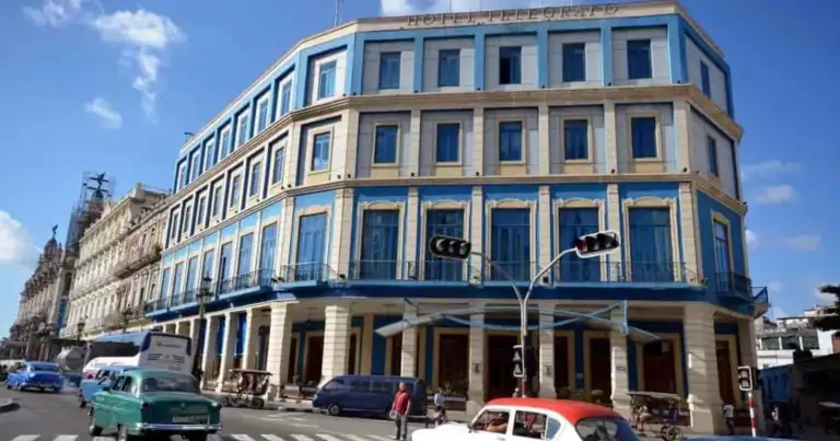 Edificio histórico de cuatro plantas con fachada azul pálido y blanco en calle urbana