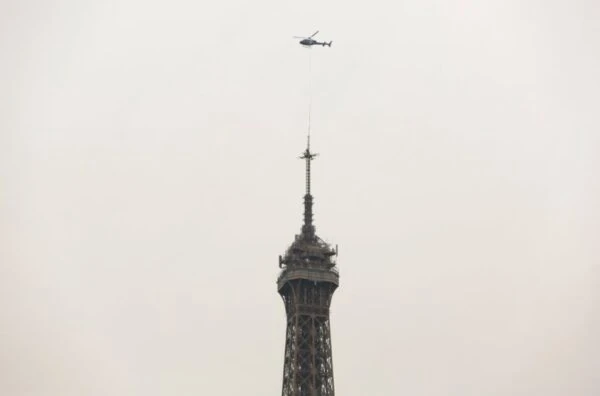 Punta de la Torre Eiffel contra cielo nublado con avioneta