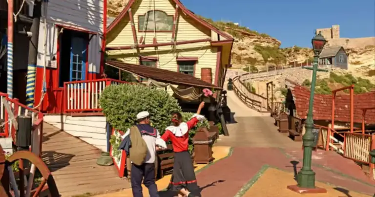 Pueblo de casas de colores con estructura de personaje animado en falda de colina rocosa