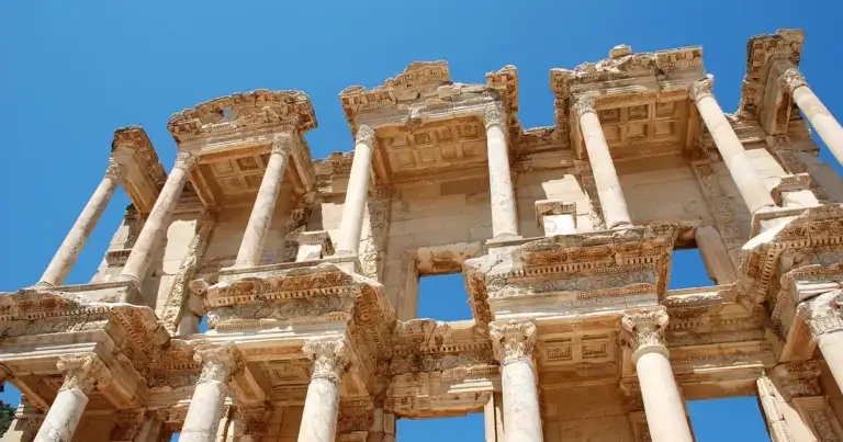 Templo antiguo con columnas decoradas de piedra clara contra cielo azul despejado