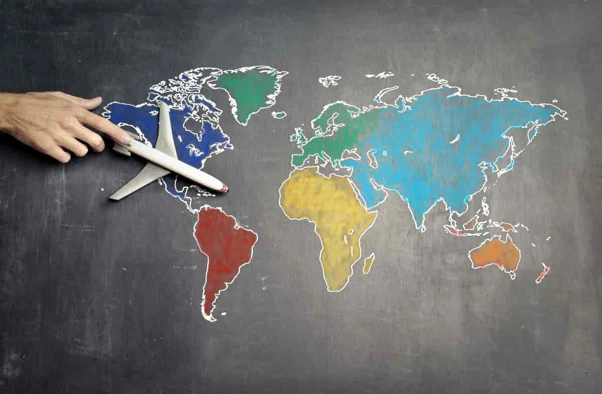 Mapa del mundo dibujado en pizarrón con mano y avión