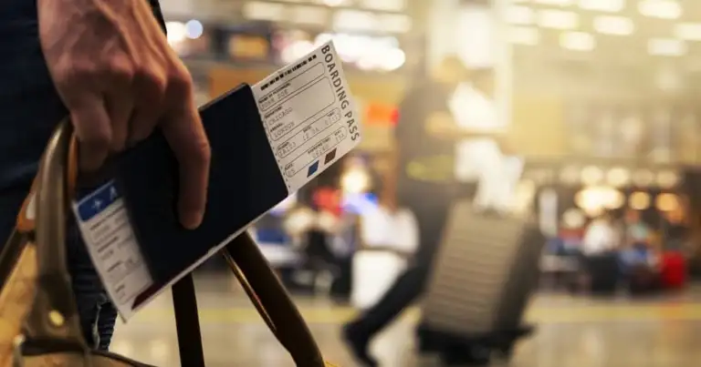 Mano sosteniendo tarjeta de embarque en terminal de aeropuerto