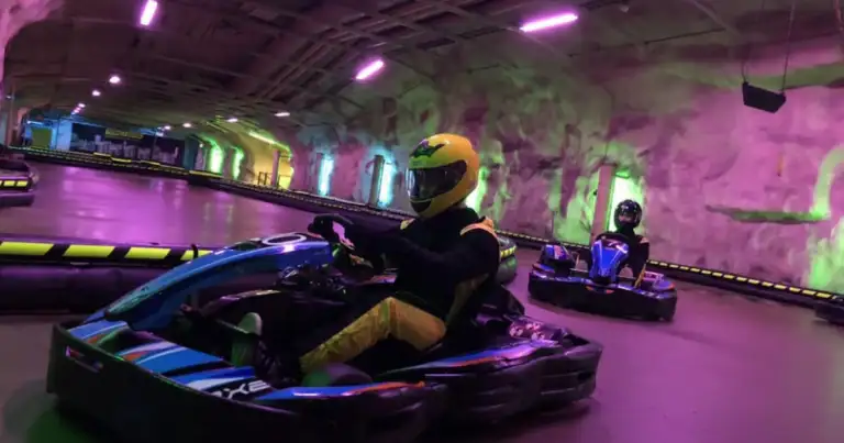Pista de karts subterránea con iluminación púrpura y personas