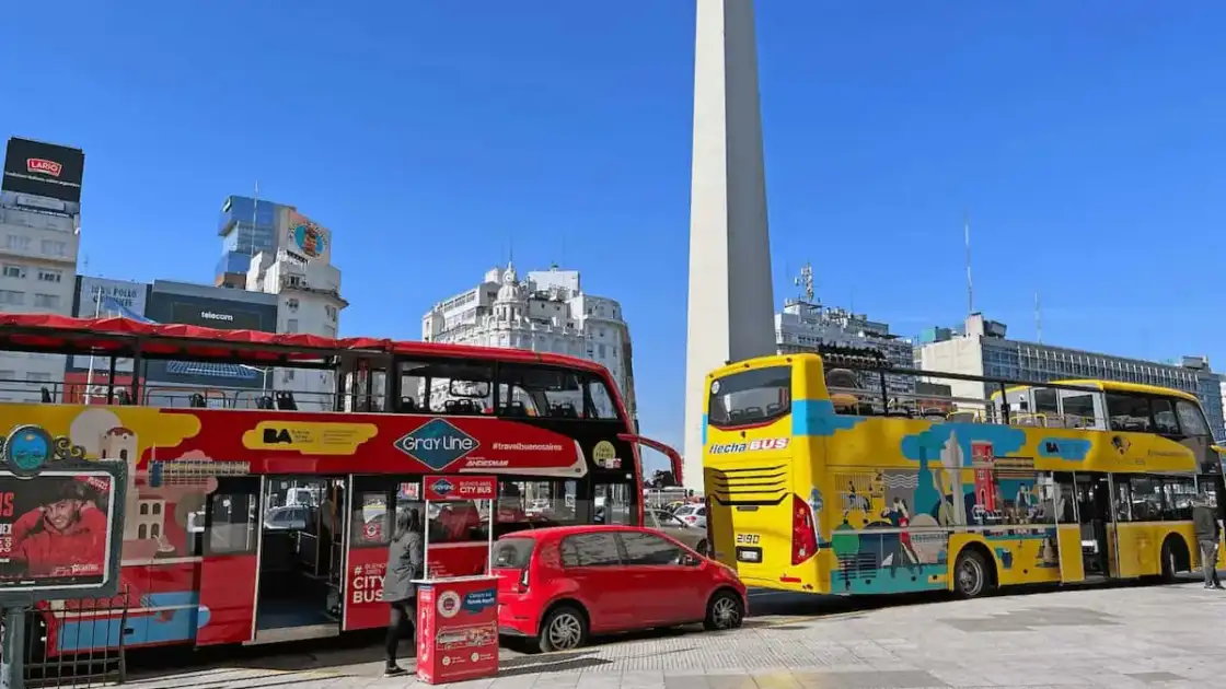 Buses turísticos frente al Obelisco de Buenos Aires en un día soleado