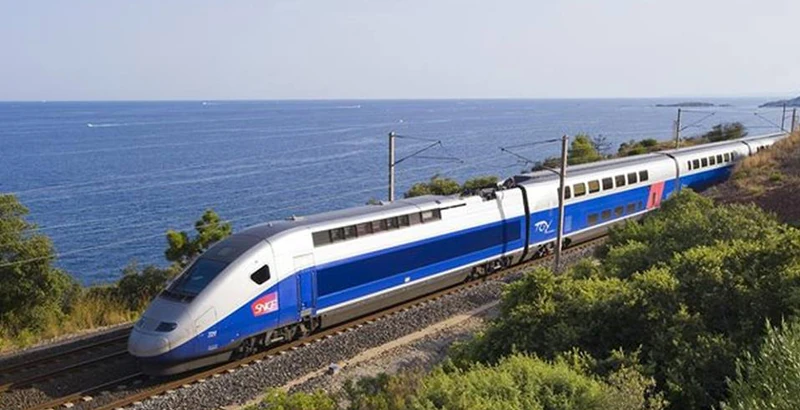 Tren blanco y azul junto al mar Mediterráneo