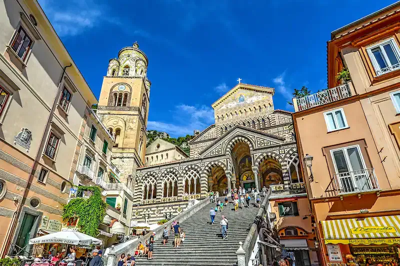 Catedral de piedra calcárea con campanario y escalinata en pueblo costero italiano